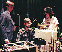 three people standing at computer table